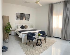 a white bedroom with a bed and a table and chairs at رخاء للغرف الفندقية in Firq