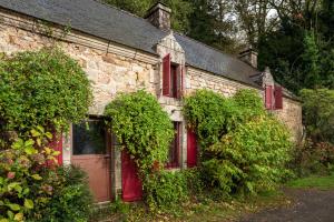 an old stone house with red windows and a door at Les gîtes Bretons in Bieuzy-les Eaux
