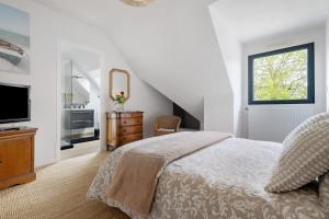 a white bedroom with a bed and a television at Chambres D'hôtes Les Goélands in Saint-Cast-le-Guildo