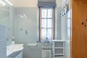 a white bathroom with a sink and a window at Simona in Fetovaia
