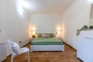 a white bedroom with a bed and a white chair at Casa Rinascita con Piscina Privata in Nulvi +28 photos