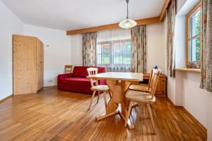 a living room with a table and chairs and a red couch at Lindenhof Apt 9 in Vandoies +12 photos