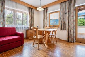 a living room with a red couch and a table and chairs at Lindenhof Apt 9 in Vandoies