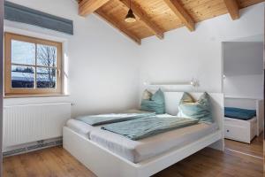 a white bedroom with a bed and a window at Schnitzer Ferienwohnung in Görisried