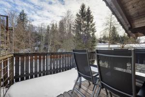 two chairs sitting on a deck in the snow at Schnitzer Ferienwohnung in Görisried