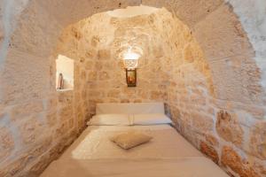 a small room with a bed in a stone wall at Trullo Milù in San Michele Salentino +23 photos
