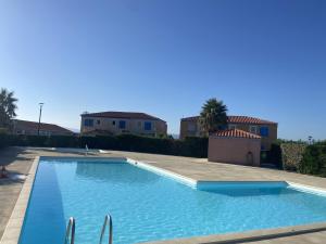 a large blue swimming pool in a yard with houses at Maison Goéland in Le Barcarès