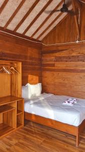a bedroom with a bed in a wooden room at Saluvi Hill's in Pulau Sarang