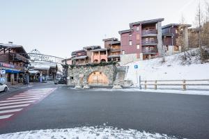 a street with a stone building and a gate with snow at Appartement 46 - Les Coches in La Plagne Tarentaise