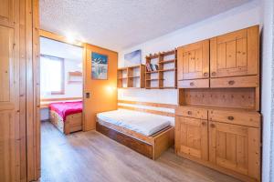 a bedroom with two beds and wooden cabinets at Appartement 46 - Les Coches in La Plagne Tarentaise