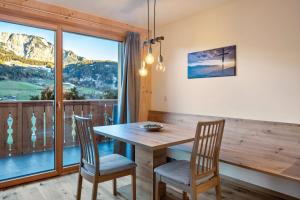 a dining room with a table and chairs and a large window at Mittnackerhof Apartment Ringelblume in Sarntal