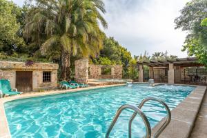 a large swimming pool with blue chairs and palm trees at La Carrasca in Catral