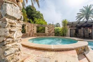 a swimming pool with a stone wall next to a stone building at La Carrasca in Catral