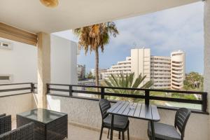 a balcony with a table and chairs and a view of the city at Lirio Blanco de las Dunas Canarias in Playa del Ingles