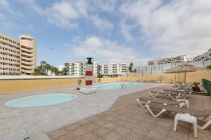 a swimming pool with two lounge chairs and a lighthouse at Lirio Blanco de las Dunas Canarias in Playa del Ingles