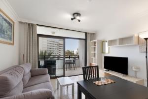 a living room with a couch and a table at Lirio Blanco de las Dunas Canarias in Playa del Ingles