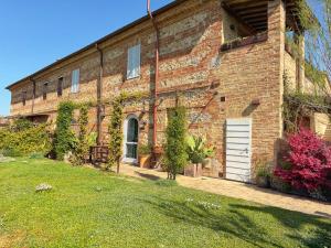 a brick building with a white door and a yard at Guardastrada Country House in Monteroni dʼArbia