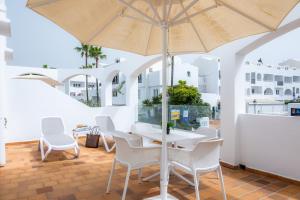 a table and chairs with an umbrella on a patio at White suites 2 in Cala d´Or