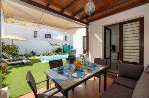 a patio with a table and chairs and a pool at Villa Petruca in Playa Blanca