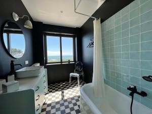 a bathroom with a tub and a sink and a bath tub at Villa Cotton-vue mer et jacuzzi-6ch in Plobannalec-Lesconil +29 photos