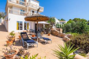 a patio with chairs and an umbrella in front of a house at Villa Sol in Cala Figuera