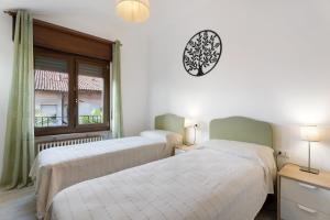 two beds in a room with a clock on the wall at Mansarda Vialba in Germignaga