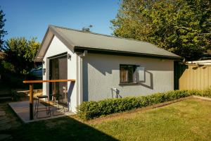 a small white house with a chair in a yard at Montblu at Echo Point in Katoomba