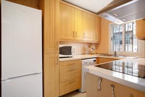 a kitchen with wooden cabinets and a white refrigerator at Prealsa Benalmádena in Benalmádena