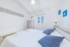 a white bedroom with a bed and two pillows at Can Blau in Portocolom