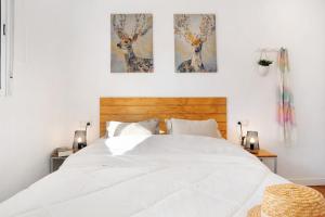 a bedroom with a white bed with two paintings on the wall at Zahora Qg in Barbate
