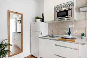 a white kitchen with a sink and a microwave at Zahora Qg in Barbate