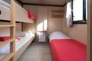a bedroom with two bunk beds and a red blanket at Chalet 25m2 - Pierres Noires in Plouhinec