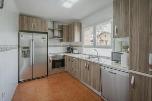 a kitchen with wooden cabinets and stainless steel appliances at Los Mirlos in Navaluenga
