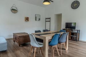 a dining room with a wooden table and blue chairs at Gite Berclois in Bercloux