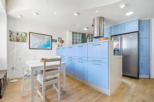 a kitchen with blue cabinets and a table and a refrigerator at Voramar in Torredembarra