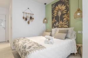 a bedroom with a white bed with two towels on it at Apartamento Black Palm 1 9 in Tarifa +17 photos