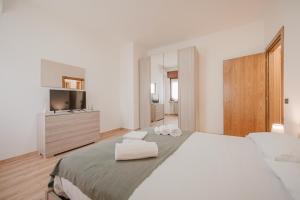 a white bedroom with a large bed and a television at La Fenice Private Gardent Free in Rivoli Veronese