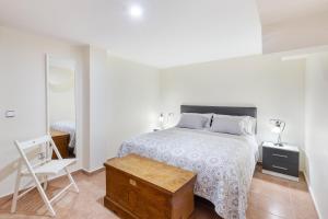 a white bedroom with a bed and a chair at Semisótano in Cartagena +16 photos