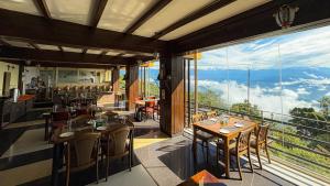 a restaurant with tables and chairs and a large window at Hotel Green Valley Nagarkot in Nagarkot