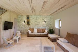 a living room with a couch and a stone wall at Gîte Le Chalimont in Saint-Julien-en-Vercors
