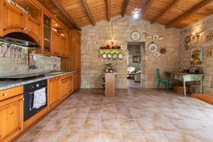 a large kitchen with wooden cabinets and a stone wall at Casa Il Carrubbo in Modica