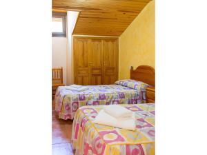 two beds in a room with wooden ceilings at Peña Yerga in Hospital