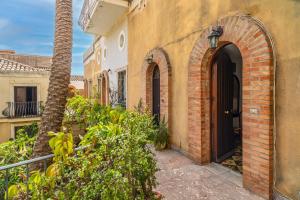 an arched doorway to a building with a palm tree at Casa Florio in Taormina