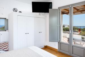 a bedroom with a bed and a tv on a wall at Luna Rossa Milos - Chili Moon in Provatas