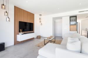 a white living room with a white couch and a tv at Chalet con Piscina en San Javier in San Javier