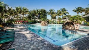 a large swimming pool with palm trees in a resort at GreenLinks Golf Villas at Lely Resort in Naples