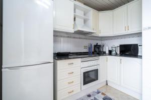 a kitchen with white cabinets and a refrigerator at Atico Duplex Pepe y Rosi in Cunit