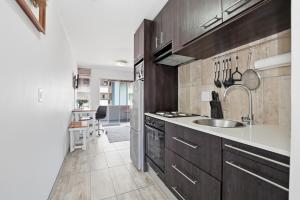 a kitchen with dark wood cabinets and a sink at Nautica by the Sea in Cape Town