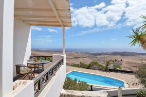 a villa with a swimming pool and a table at Finca La Calerita C in Yaiza