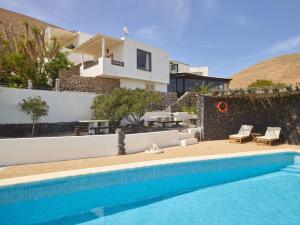 a villa with a swimming pool in front of a house at Finca La Calerita C in Yaiza